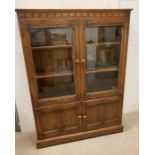 An Ercol glazed bookcase with cupboard under (138cm x 30cm x 101cm)