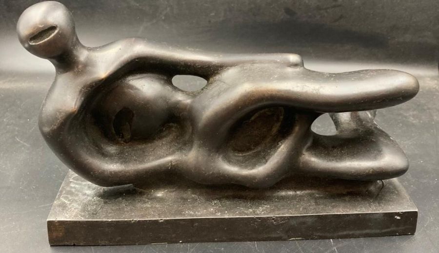 A reclining abstract bronze figure, signed Henry Moore