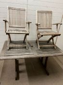 Two weathered folding teak chairs and a teak garden table (150 cm x 90cm)