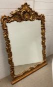 An ornate gilt wood framed mirror with leaf detail 98cm x 135cm