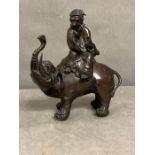 An Oriental bronze of a figure riding an elephant, approx 20cm H.
