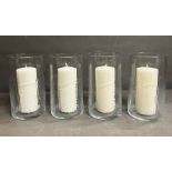 Four glass hurricane lamps with candles