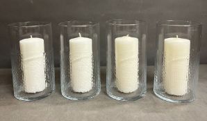 Four glass hurricane lamps with candles