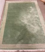 A wool rug with green grounds and a string white boarder 250cm x 166cm
