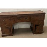 An oak knee hole desk with drop handles and lower cupboards below (H93cm W176cm D48cm)