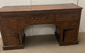 An oak knee hole desk with drop handles and lower cupboards below (H93cm W176cm D48cm)
