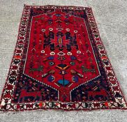 An Iran handknotted carpet/rug, red ground with centre depicting birds and other animals with blue