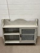 A painted wall unit with hinged wire mesh door.