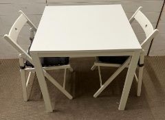 A white Ikea table with two folding chairs