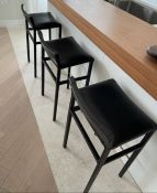 A set of three kitchen island stools, metal frames and black leather seats