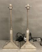 A pair of square columned stainless steel bedside lamps