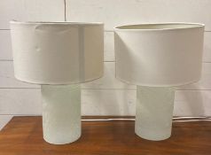 A pair of cylindrical cracked glass table lamps with white shades