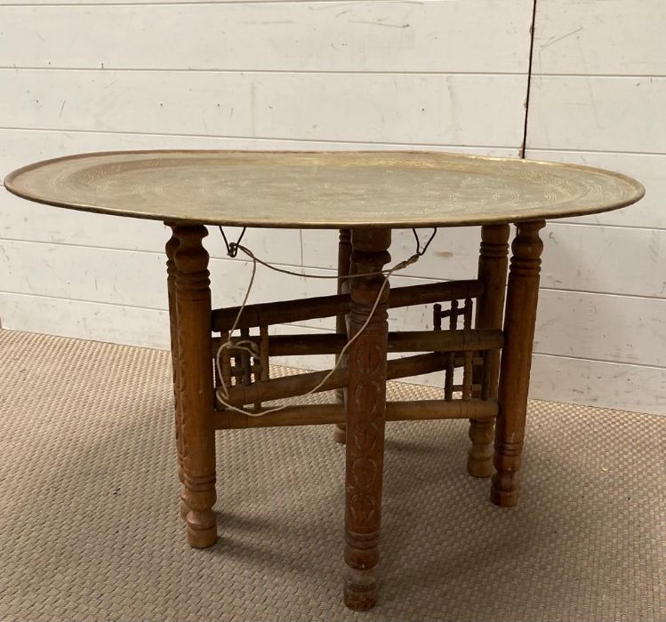 An Arabic brass table on collapsible wooden legs