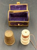 A vintage brass thimble in a brass trunk styled holder.