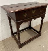 An oak single drawer side table with brass handles on turned legs