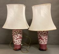 A pair of burgundy and white oriental style ceramic lamps on wooden bases AF