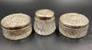 A selection of three silver lidded glass pots