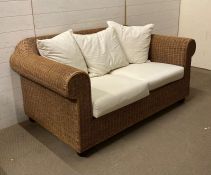 A two seater wicker sofa with white linen upholstered cushions AF
