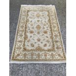 A beige ground rug with floral pattern and geometric boarder (120cm x 190cm)