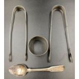 A selection of four silver items to include two sugar nips, napkin ring and a teaspoon
