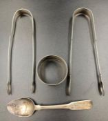 A selection of four silver items to include two sugar nips, napkin ring and a teaspoon