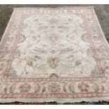 A beige ground rug, decorated with pink scrolling vines and geometric boarder (206cm 272cm)
