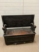 An oak carved monks bench with lion supports, heavily carved front and lift up seat (H74cm W120cm