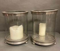 A pair of white metal and glass storm lanterns