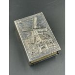 A silver matchbox with a windmill design