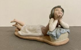 A Nao figurine of a girl lying down blowing a kiss