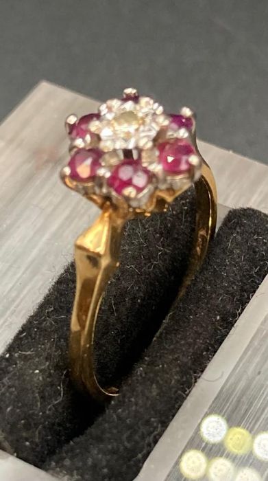 A ruby and diamond ring in a daisy style with central diamond surrounded by six rubies (