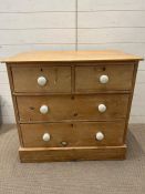 A pine two over two chest of drawers with white knob handles (H81cm W85cm D74cn)
