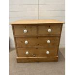 A pine two over two chest of drawers with white knob handles (H81cm W85cm D74cn)
