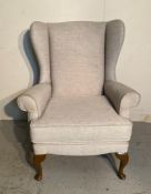A beige upholstered wing back arm chair