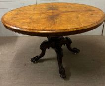 A walnut center table on scrolling feet and castors (73cm x 89cm x 124cm)