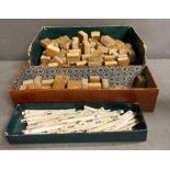 A selection of wooden mahjong pieces along with a volume of bone and some plastic betting sticks