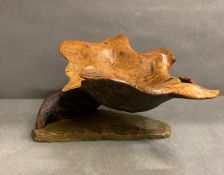 A cantilevered bowl in carved oak on a stone plinth. (Approximate Measurements 16.5cm H x 36 cm W)