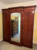 A Victorian mahogany triple gentleman's wardrobe with central mirrored door. Opening to three pull