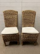 A pair of seagrass chairs with cream seat pads