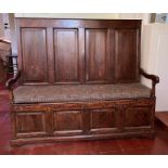 An antique four panel settle with open arms, hinged seat with internal storage (H135cm W158cm