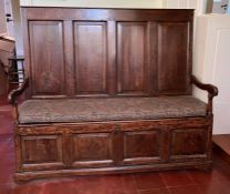 An antique four panel settle with open arms, hinged seat with internal storage (H135cm W158cm
