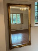 A gilt wall mirror with scrolling details to corners (74cm x 135cm)