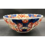 An Imari pattern bowl underglaze blue with overglaze enamels with a vase of flowers on a table