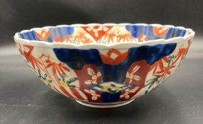An Imari pattern bowl underglaze blue with overglaze enamels with a vase of flowers on a table