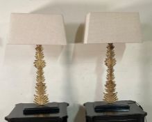 A pair of contemporary table lamps with a leaf design to centre