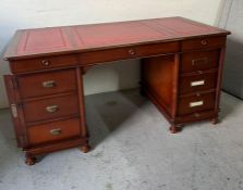 A partners desk with brass grab handles, lockable sides, red leather top and wooden measuring