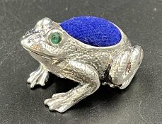 A silver pin cushion in the form of a frog with gem set eyes