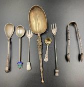 A selection of silver curios to include mustard spoons, shell sugar nips, pickle fork, and an ornate