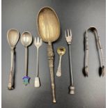 A selection of silver curios to include mustard spoons, shell sugar nips, pickle fork, and an ornate