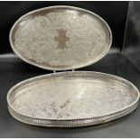Two white metal trays with pierced sides with decorated trays.